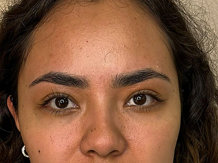 Mirada de frente de una clienta con cejas pobladas, oscuras y con forma natural.