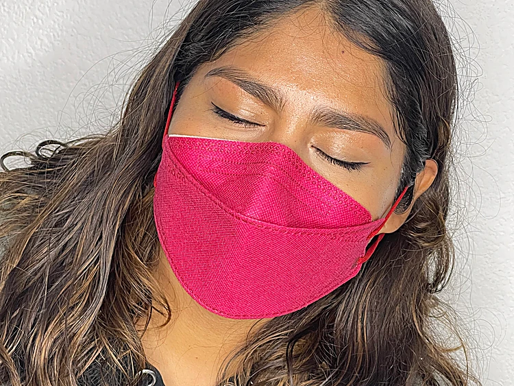 Clienta con los ojos cerrados y cubrebocas fucsia, con las cejas definidas y las pestañas largas y curvas.