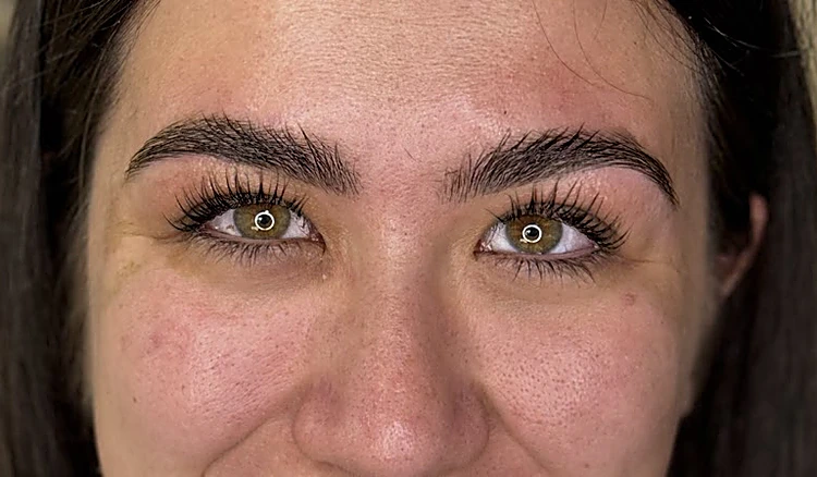 Ojos de una clienta con pestañas levantadas y cejas pobladas y definidas.